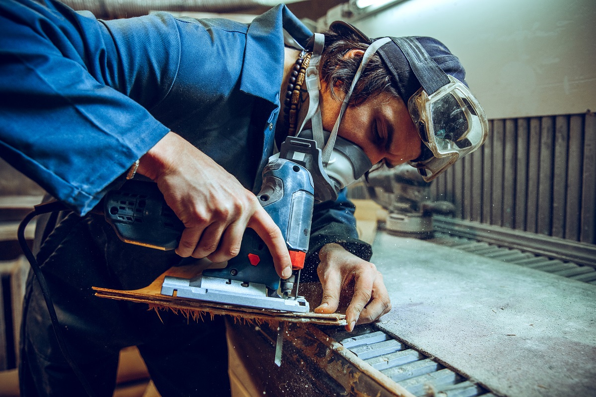 Carpenter using circular saw for cutting wooden boards.