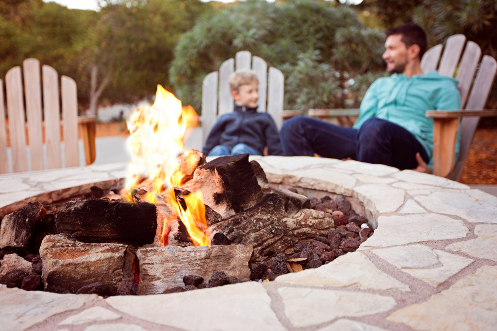 father and son chilling around an outdoor fireplace