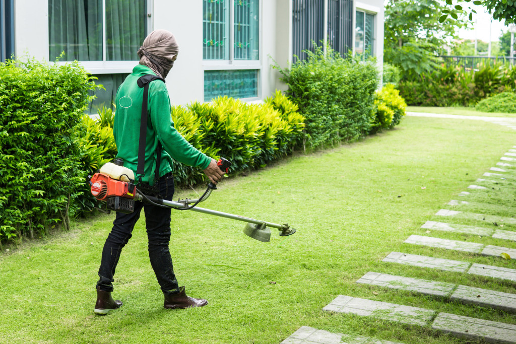 a man in a yard cutting grass using a handheld grass cutter