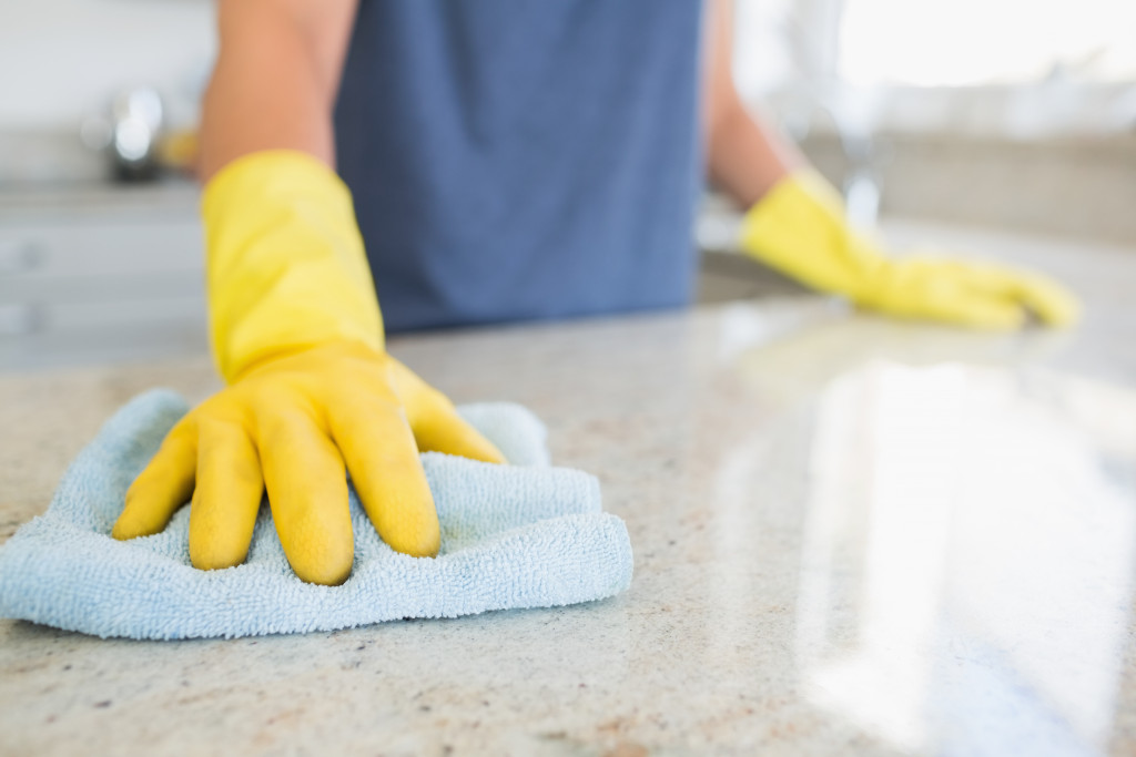 A person cleaning the kitchen counter with a cloth