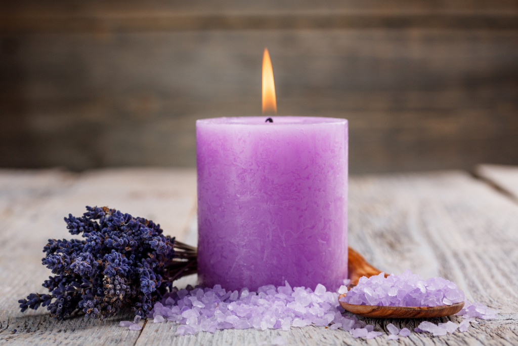A purple scented candle, lavenders, and purple salts