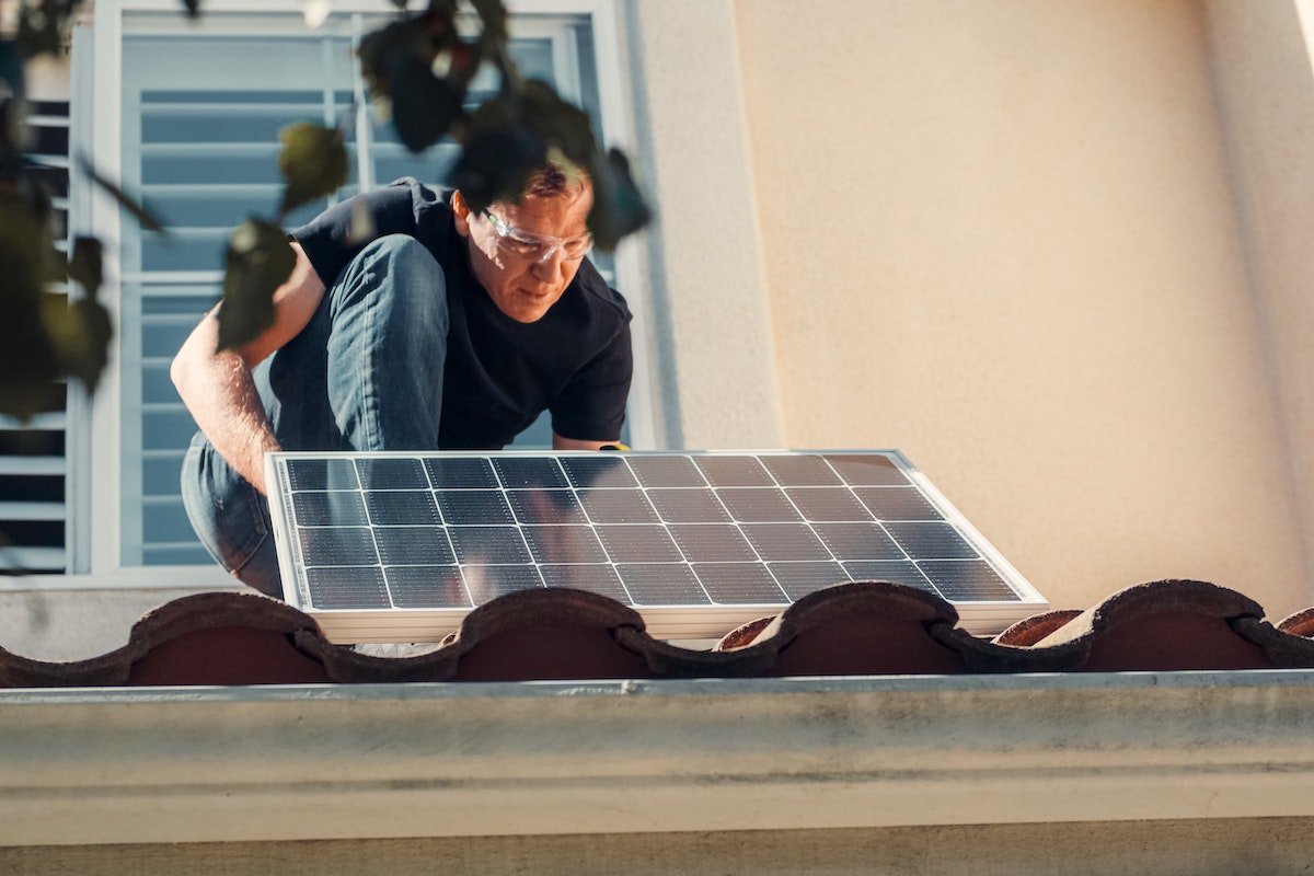 man installing solar panel on roof