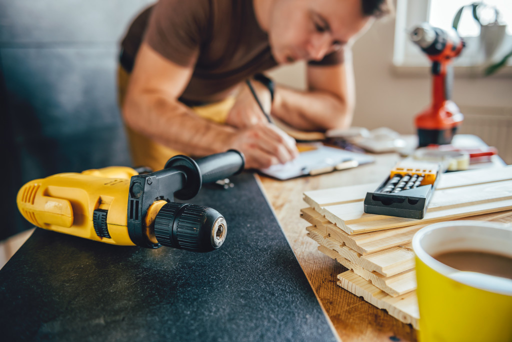 male designing home renovation with coffee, drill, and wood on the side