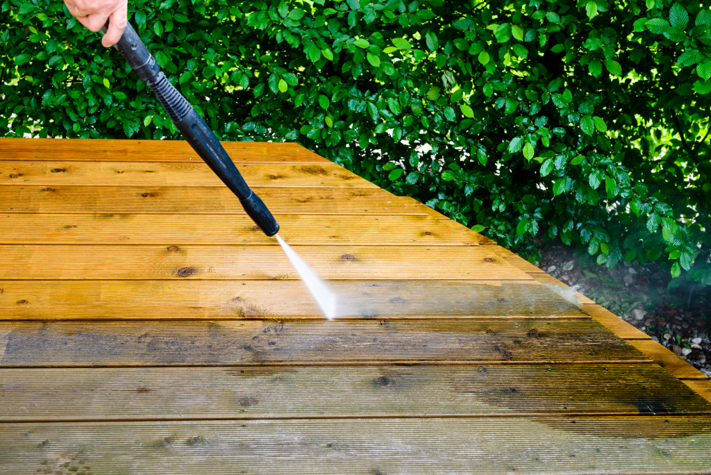 Homeowner cleaning a deck with a power washer.
