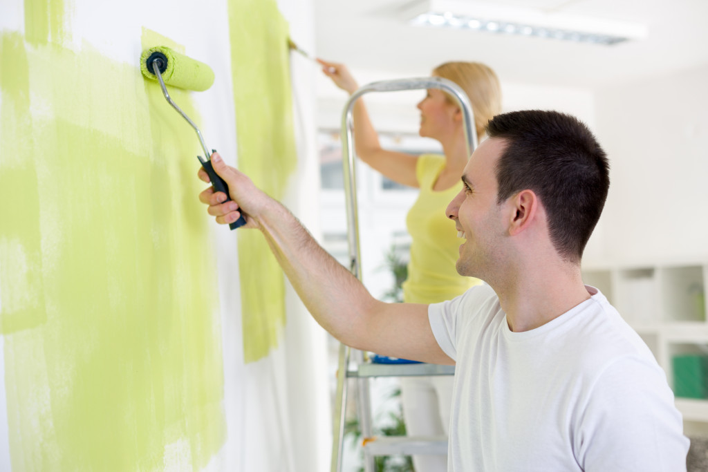 Young couple painting the interior of their home.