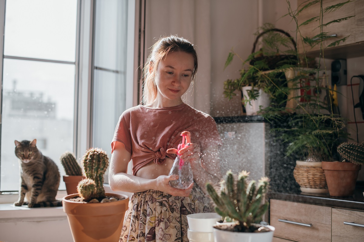 Young woman taking care of plants inside a home.